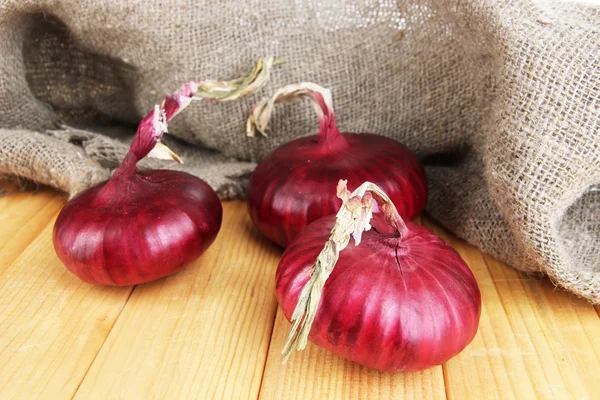 Frische rote Zwiebeln auf Holztisch — Stockfoto