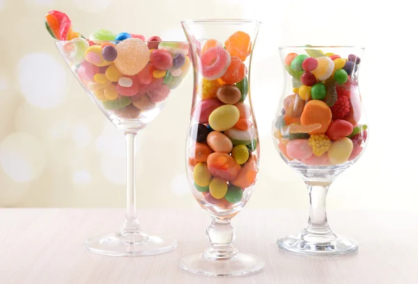 Différents bonbons aux fruits colorés dans des verres sur la table sur fond clair — Photo