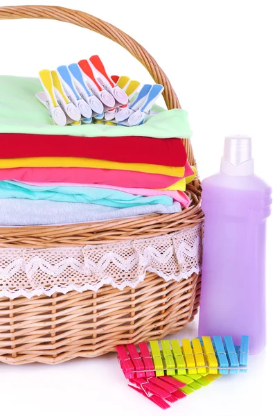 Bright clothes in laundry basket, pins and bottle with shampoo for washing, isolated on white — Stock Photo, Image