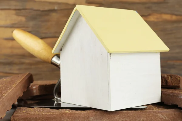 Casa giocattolo in legno su spatola e piastrelle su sfondo di legno, primo piano — Foto Stock