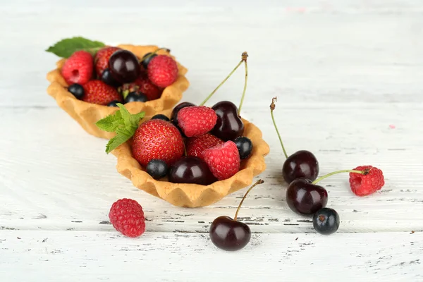 Tasty tartlets with berries on wooden table — Stock Photo, Image