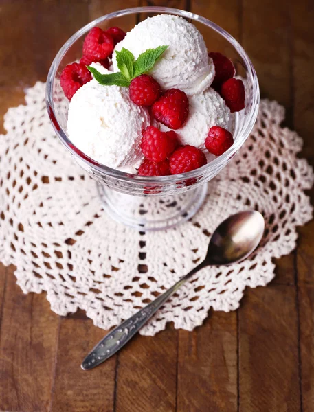 Creamy ice cream with raspberries on plate in glass bowl, on color wooden background — Stock Photo, Image