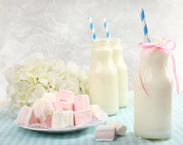 Milch in Flaschen mit Papierhalmen auf dem Tisch — Stockfoto