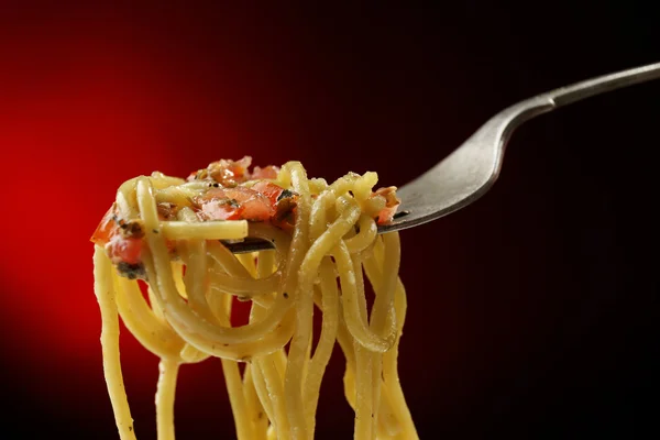 Espaguetis de pasta italiana sobre tenedor sobre fondo oscuro — Foto de Stock