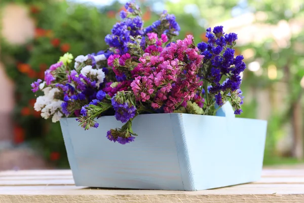 Vackra blommor i trä korgen på bordet, utomhus — Stockfoto