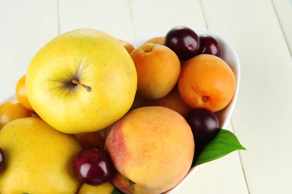 Bright summer fruits in plate on wooden table close-up — Stock Photo, Image