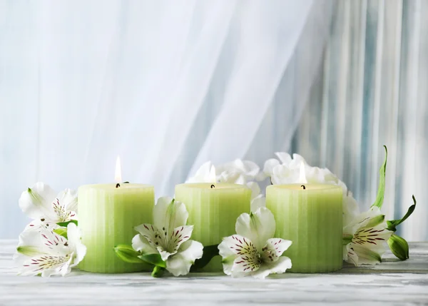 Piękne świece z kwiatami na drewnianym stole, na ciemnym tle — Zdjęcie stockowe