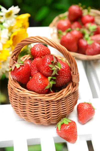 Zralé sladké jahody v proutěném koši na stole v zahradě — Stock fotografie