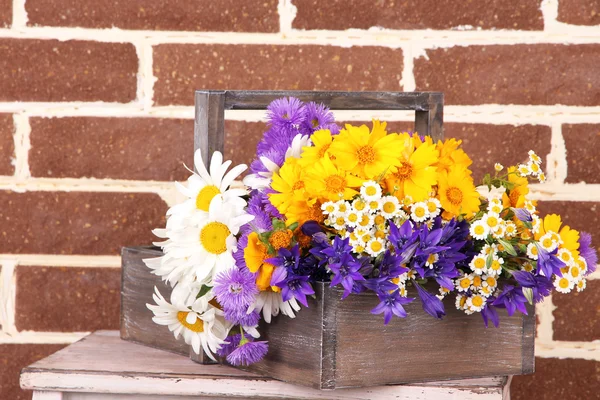 Hermosas flores en caja sobre fondo de pared de ladrillo —  Fotos de Stock
