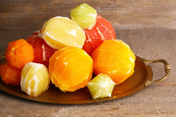 Citrus fruits without skin on tray, on wooden background — Stock Photo, Image