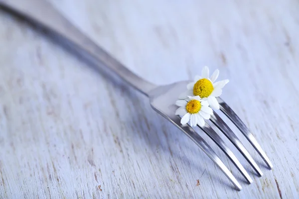 Fork with daisy flower, on wooden background — Stock Photo, Image
