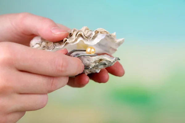 Hand with tweezers holding pearl — Stock Photo, Image