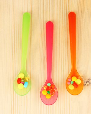 ahşap arka plan üzerinde renkli hapları ile plastik kaşık