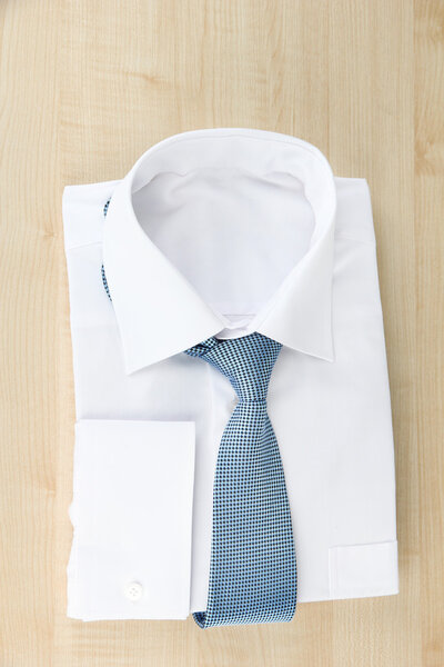 New white man's shirt with color tie on wooden background