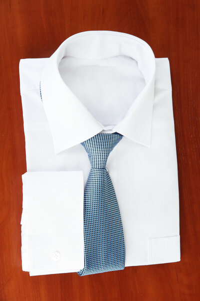 New white man's shirt with color tie on wooden background