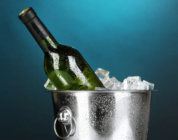 Bouteille de vin dans un seau à glace sur fond bleu foncé — Photo