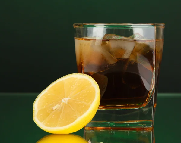Pohár whiskyt jéggel és citrommal zöld háttér — Stock Fotó