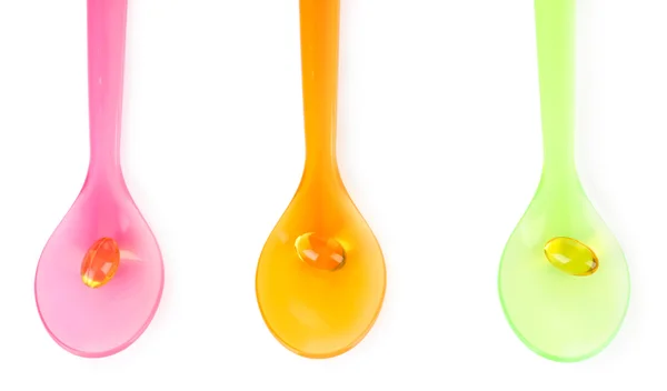 Plastic spoons with color pills — Stock Photo, Image