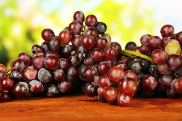 Свежий виноград, на деревянном столе, на ярком фоне — стоковое фото