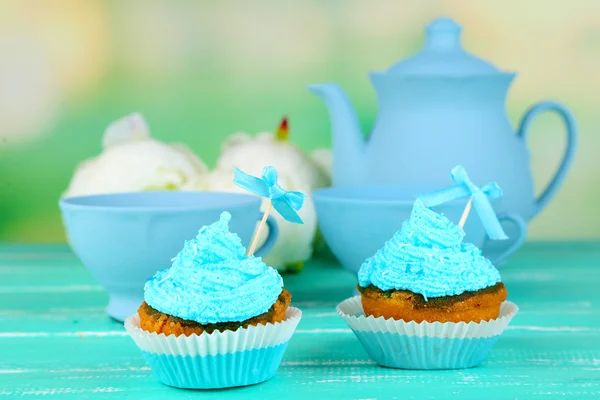 Tasty cup cakes with cream on blue wooden table — Stock Photo, Image