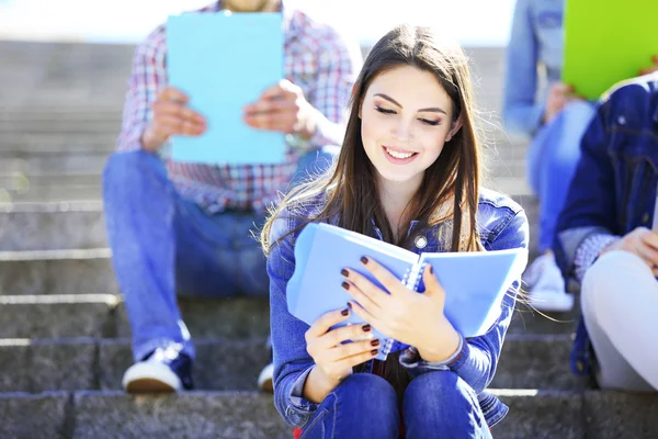 Heureux étudiants assis sur les escaliers dans le parc — Photo