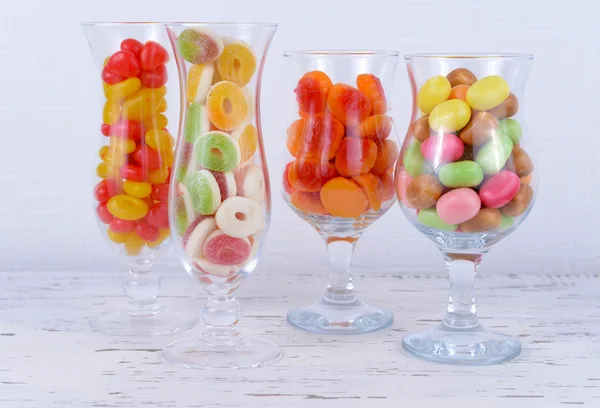 Diferentes dulces de frutas de colores en vasos en la mesa sobre fondo claro — Foto de Stock