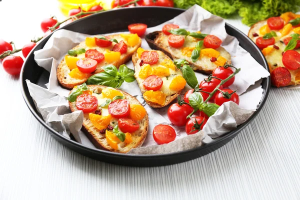 Sabroso bruschetta con tomates en la cacerola, sobre la mesa — Foto de Stock