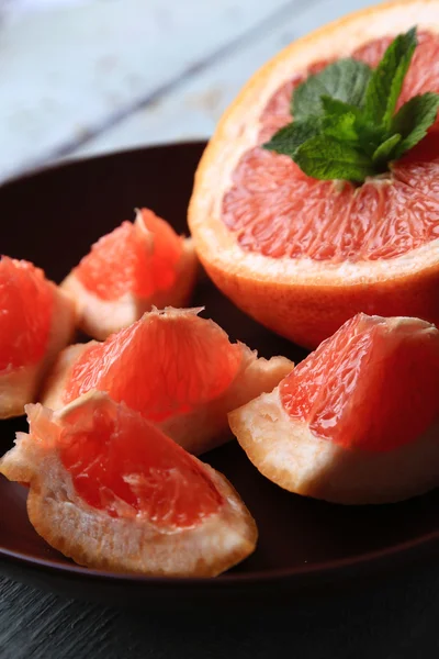 Ripe grapefruits on plate on color wooden background — Stock Photo, Image