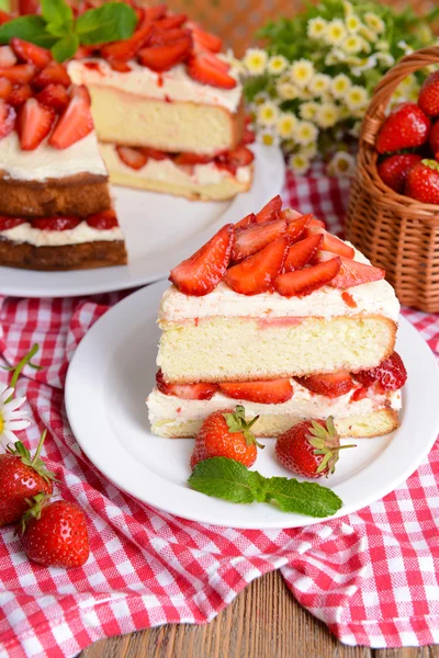 Delicious biscuit cake with strawberries on table on brown background — Stock Photo, Image