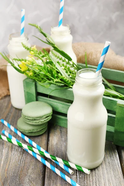 Melk in flessen met papier rietjes op tafel — Stockfoto