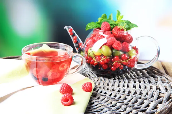 Tè rosso frutta con frutti di bosco in tazza di vetro, su tavolo di legno, su sfondo luminoso — Foto Stock