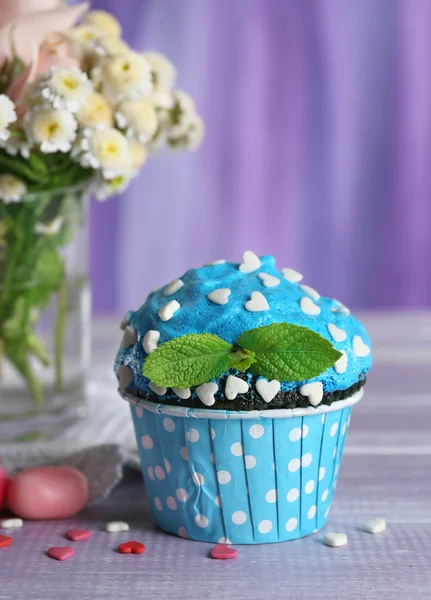 Tasty cupcake on table, on fabric background — Stock Photo, Image