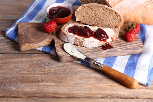 Čerstvé toasty s domácí máslem a jahodovým džemem, na dřevěné pozadí — Stock fotografie