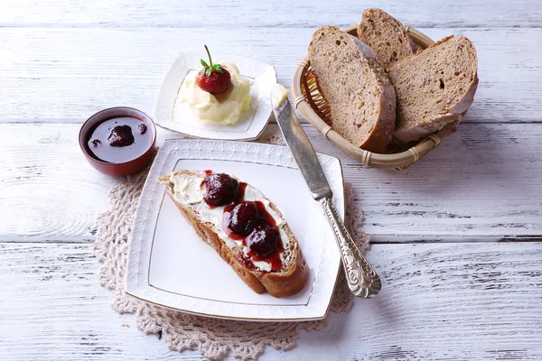 Verse toast met zelfgemaakte boter en strawberry jam op lichte houten achtergrond — Stockfoto