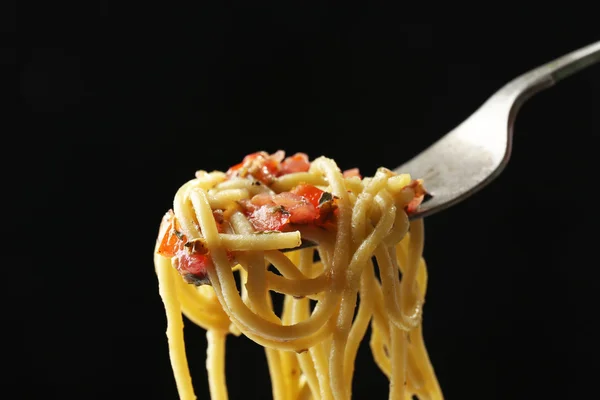 Espaguetis de pasta italiana sobre tenedor sobre fondo negro — Foto de Stock
