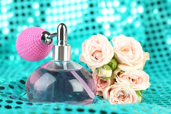 Perfume bottle with roses on fabric background — Stock Photo, Image