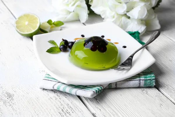 Jalea verde con bayas de grosella negra y salsa, sobre fondo de madera — Foto de Stock