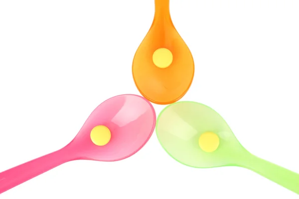 Plastic spoons with color pills — Stock Photo, Image