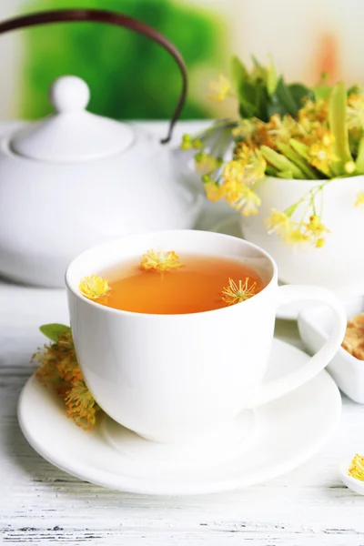 Chá de ervas saboroso com flores de tília na mesa de madeira — Fotografia de Stock