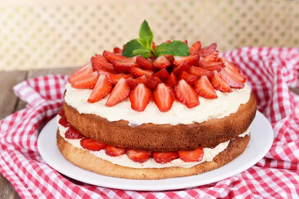 Delicious biscuit cake with strawberries on table on beige background — Stock Photo, Image