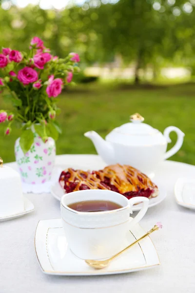 Mesa de centro con tazas de té y sabroso pastel en el jardín —  Fotos de Stock