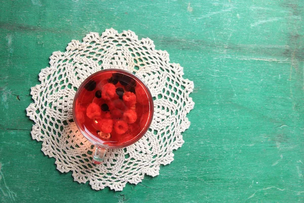 Frukt rött te med vilda bär i glas cup, på trä bakgrund — Stockfoto