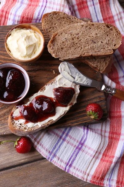 Ahşap arka plan üzerinde ev yapımı tereyağı ve çilek reçel taze tost — Stok fotoğraf