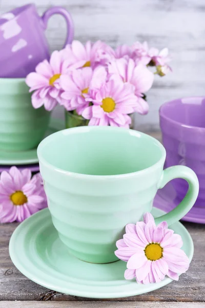 Cups and saucers with flowers on wooden background — Stock Photo, Image