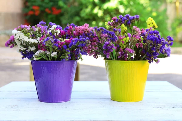 Beautiful flowers in flowerpot on wooden table, outdoors — Stock Photo, Image