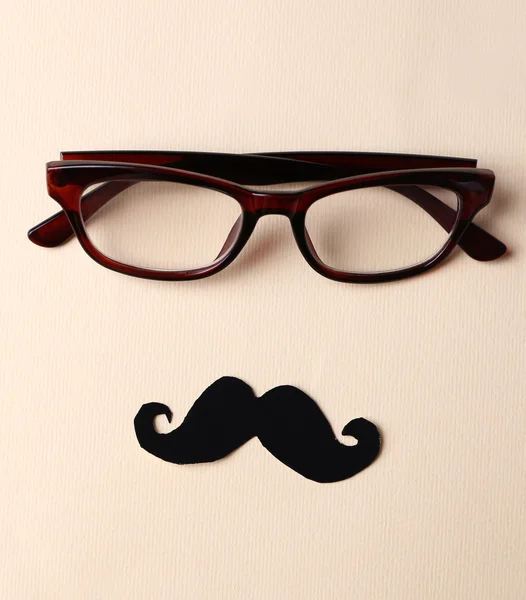 Glasses and mustache forming man face on beige background — Stock Photo, Image