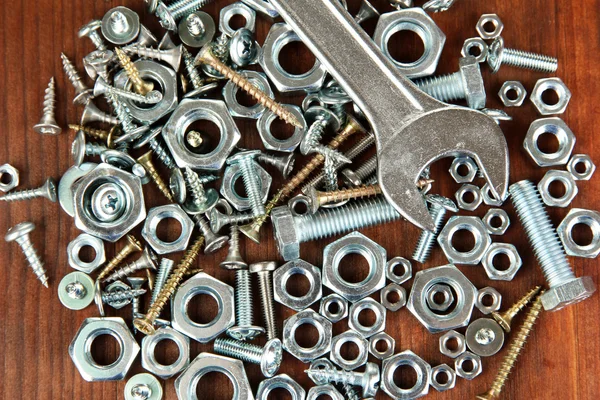 Wrench on bolts, screws and nuts on wooden table — Zdjęcie stockowe