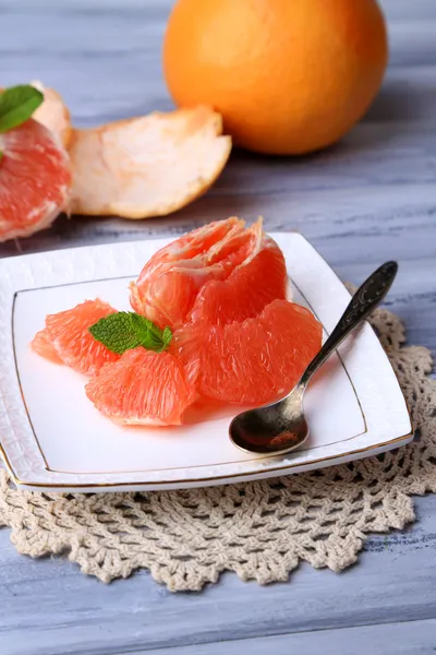 Reife geschälte Grapefruits auf Teller, auf farbigem Holzhintergrund — Stockfoto