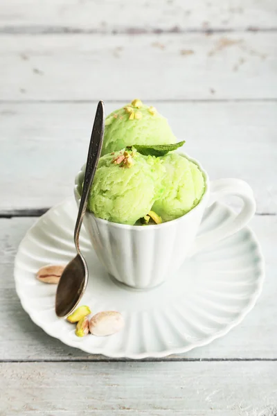 Crème glacée savoureuse aux pistaches dans une tasse sur une table en bois — Photo