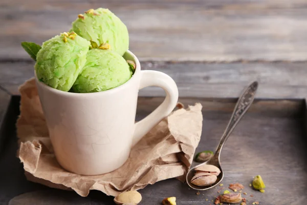 Crème glacée savoureuse aux pistaches dans une tasse sur une table en bois — Photo